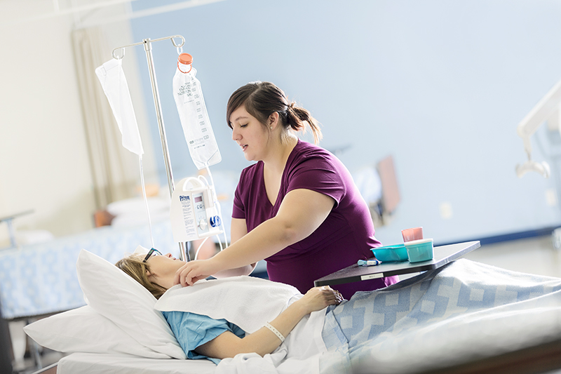 A health care aide adjusting a patient in a hospital