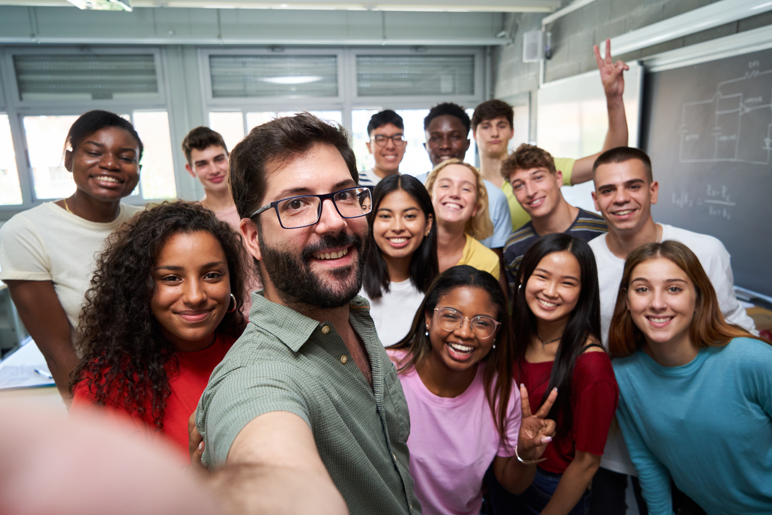 A group in a classroom taking a selfie with their teacher