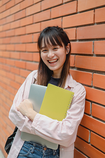 A smiling female student against a brick wall