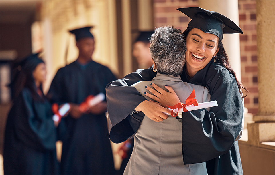 A graduate at convocation hugging their mom