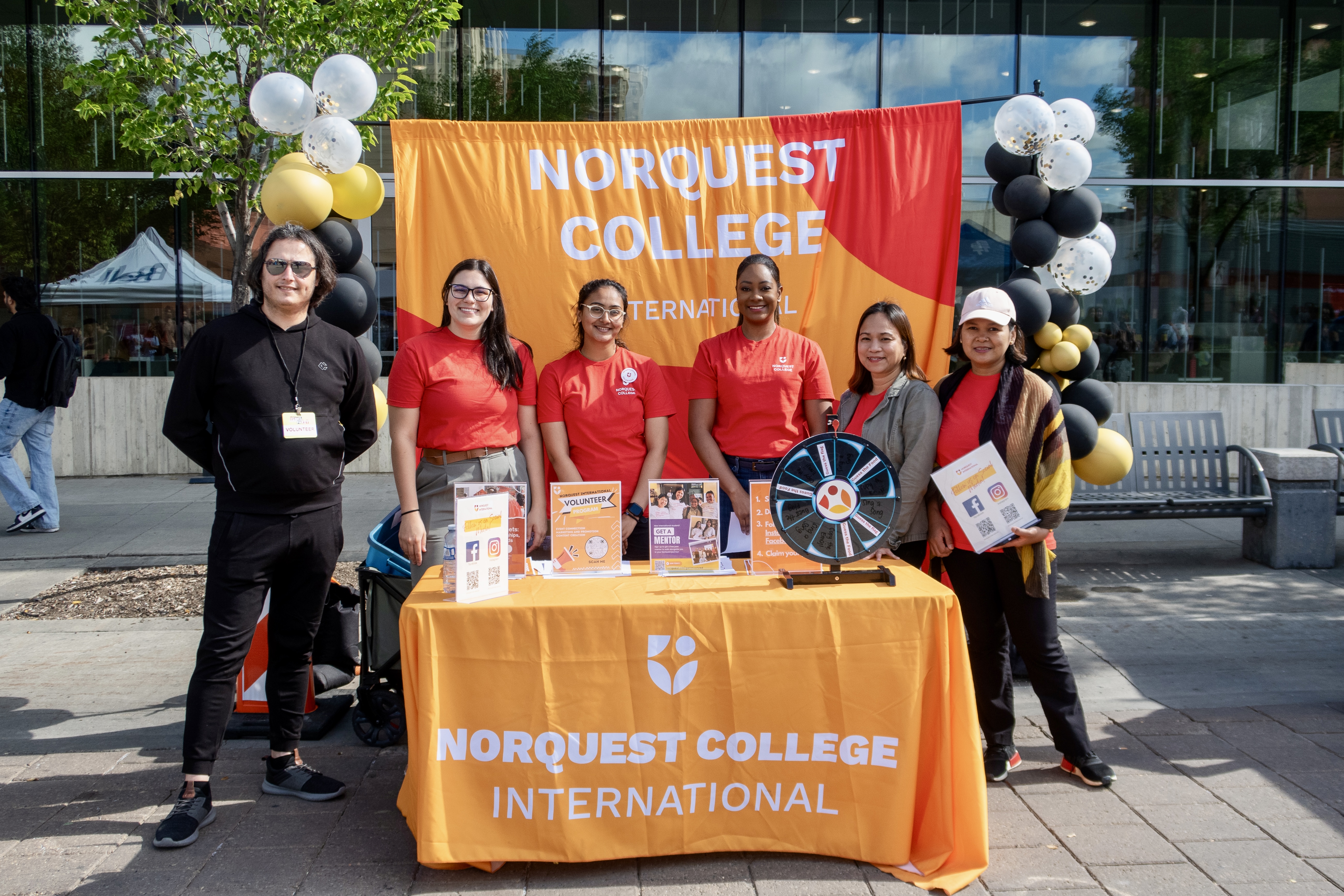 A group of NorQuest international students running an information booth outside.
