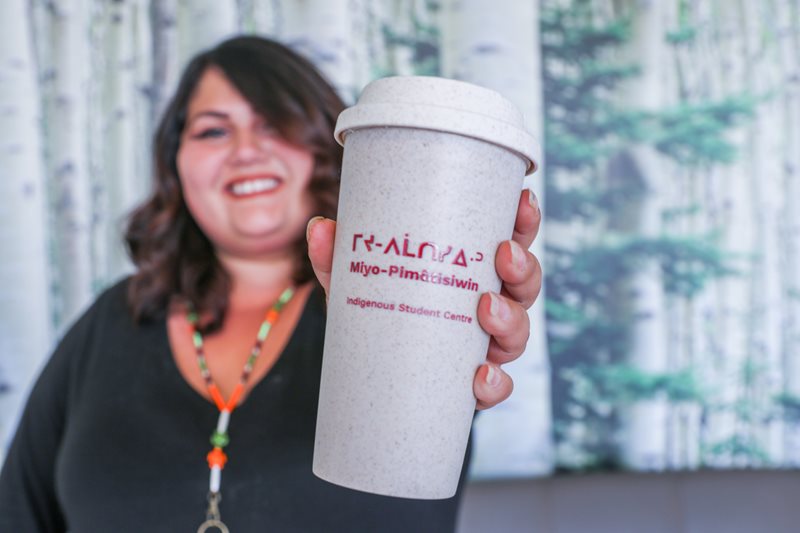 Women holding a cup that says Miyo-Pimatisiwin on it