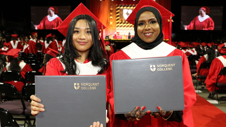Close up of two grads holding their diplomas