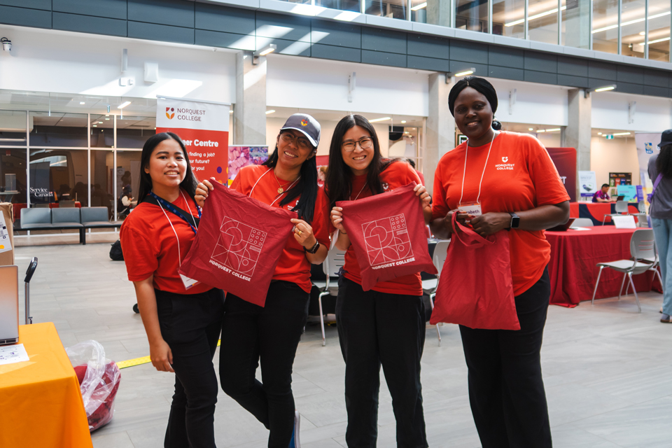 A group of NorQuest international students holding NorQuest bags