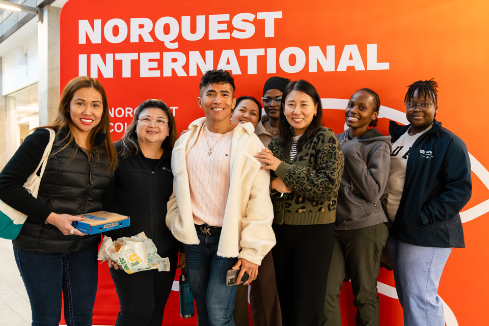International students posing for a group photo in front of a display